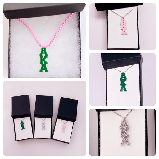 Collage showcasing various Alpha Kappa Alpha Sorority, Inc. necklaces, featuring AKA pendants in green, pink, and silver. Each necklace is elegantly presented in black gift boxes with white cushioning.